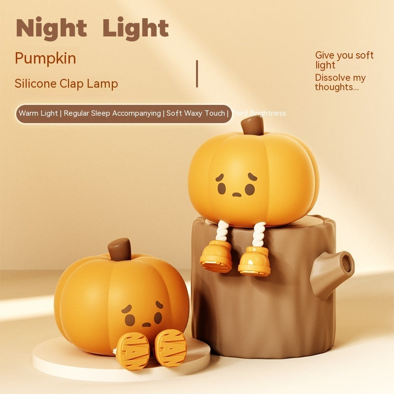 Halloween Pumpkin Silicone Night Light — two pumpkin silicone clap lamps with cute sad faces, one on a white base and one on a tree stump, advertising warm light and soft waxy touch