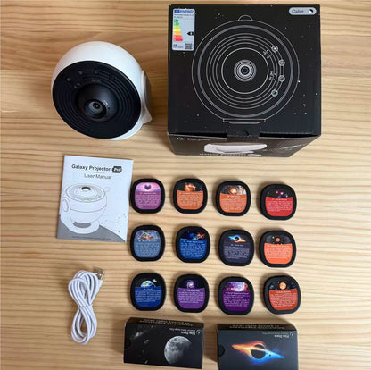 Galaxy Star Projector Light — flat lay showing white projector, product box, user manual, 12 film discs, USB cable, and accessory boxes on a wooden surface
