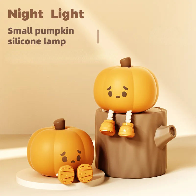 Halloween Pumpkin Silicone Night Light — two small pumpkin silicone lamps with cute sad faces and little legs, one on a white base and one on a tree stump